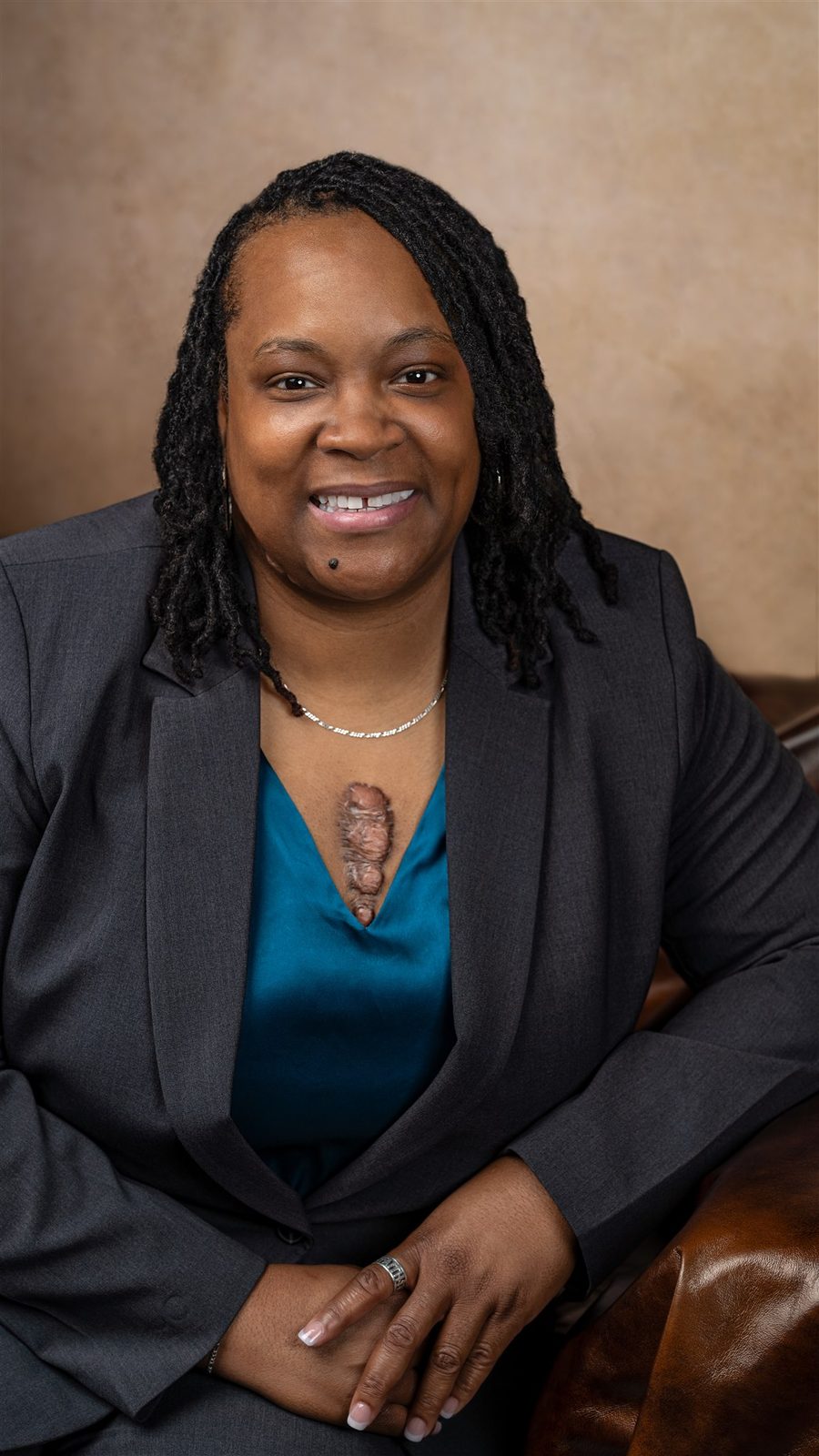 Danitza Mack, founder and CEO of D. Mack Consulting Group, seated in a charcoal suit